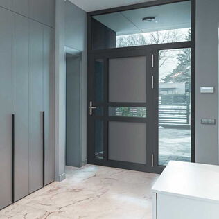 Innenansicht eines Eingangsbereichs mit ATRIS-Aluminium-Haustür H00207 mit zwei waagerechten und einer senkreichten Sprosse, Füllung teils Klarglas, teils in Grauton