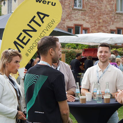Teilnehmer eines WERU-Events, die sich an einem Stehtisch im Freien unterhalten
