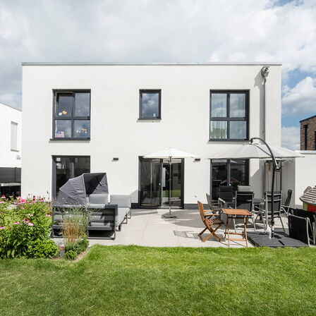 Einfamilienhaus mit Flachdach, anthraziten Fenstern und einer Terrasse und Garten
